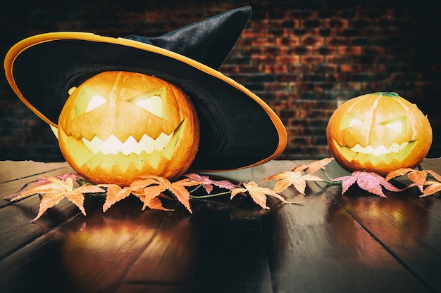 Halloween pumpkin on black wooden table with brick background. Halloween holiday concept. 