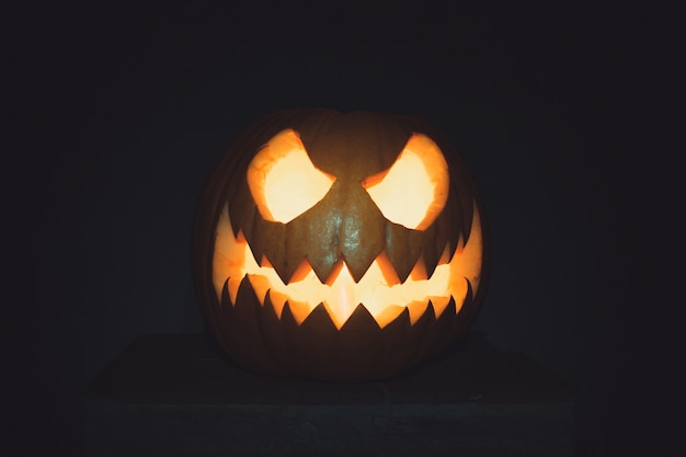 Фото Хэллоуин тыква лицо со свечой, зажженной на черном фоне жуткое лицо