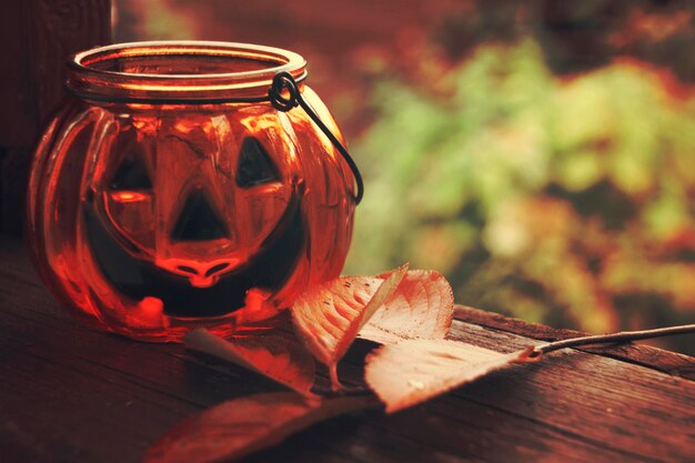 Foto candeliere in vetro zucca di halloween con foglie autunnali