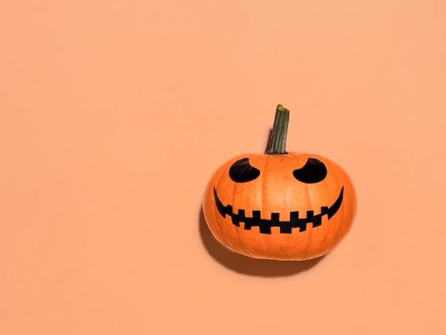 Halloween pumpkin in hand on orange background