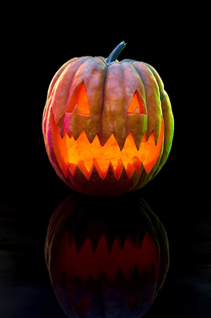 Foto jack-o-lantern della testa della zucca di halloween con il fronte diabolico spaventoso decorazione illuminata stagionale. sembra spaventoso, luce al neon colorata e sfondo scuro. vacanze. venerdì nero, saldi. notte di paura.