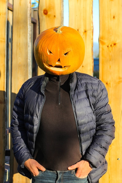 秋のジャックランタンの衣装を着たハロウィーンのカボチャの頭の男。