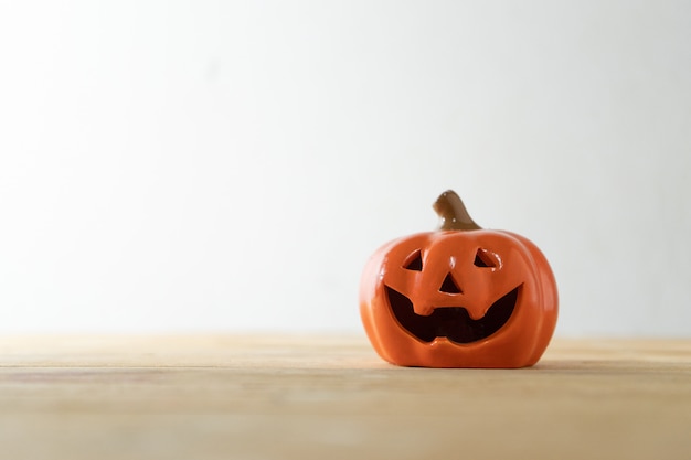 Miniatura della zucca di halloween sulla tavola di legno della plancia su fondo bianco.