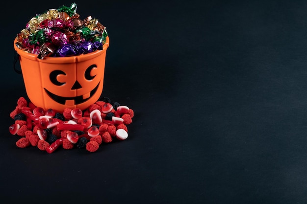 写真 ハロウィーン パンプキン 黒い背景のキャンディーで満たされたバケツ ハロウィーンの祭りと祝いのコンセプト