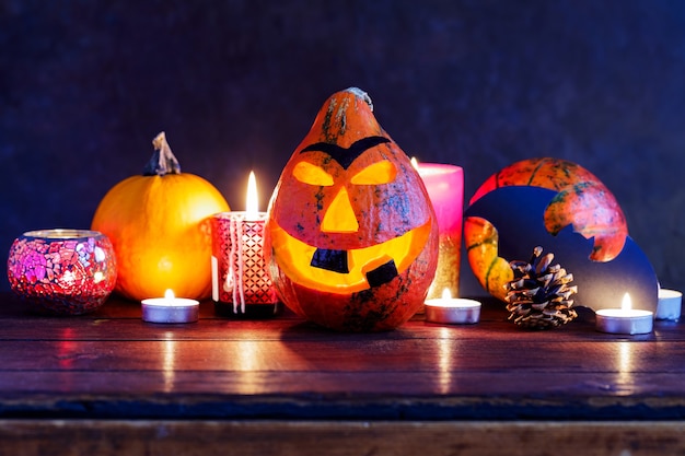 Тыква хеллоуина с зажженными свечами на темном фоне. Улыбка тыквы Хэллоуина и страшные глаза. Хеллоуинские украшения