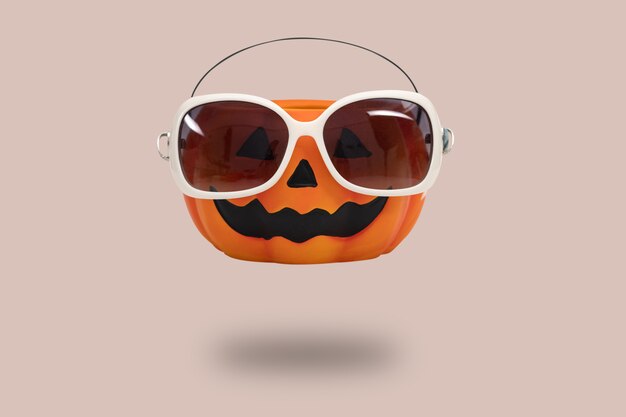 Halloween pumpkin with glasses on pink background. Halloween minimal idea concept