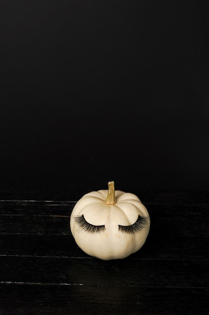 Halloween pumpkin with make up false eye lashes on black background. Halloween Holiday season concept