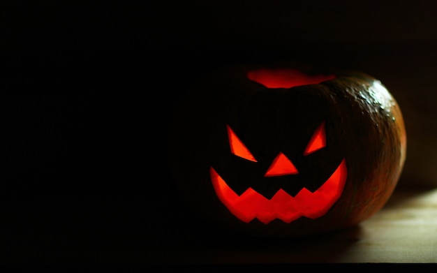 黒の背景に怖い顔のハロウィーンのカボチャ