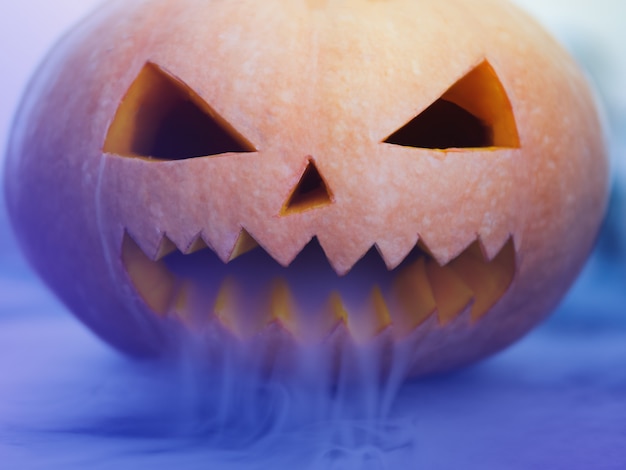 Halloween pumpkin with scary face on dark 