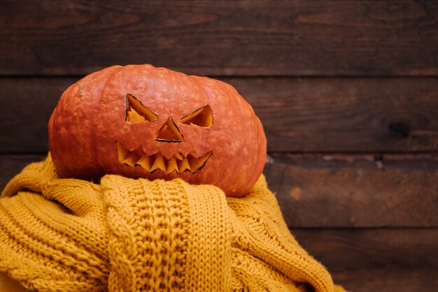 Halloween pumpkin on yellow sweater and wooden background