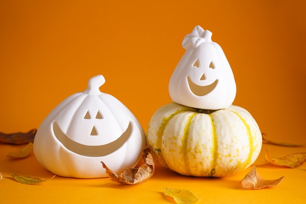 Photo halloween pumpkins, dried leaves on yellow background. halloween concept. autumn composition.