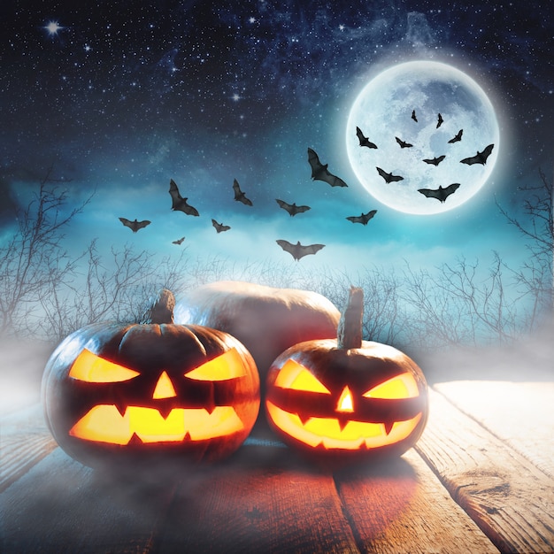 Halloween pumpkins in a mystic forest at night with full moon and bats