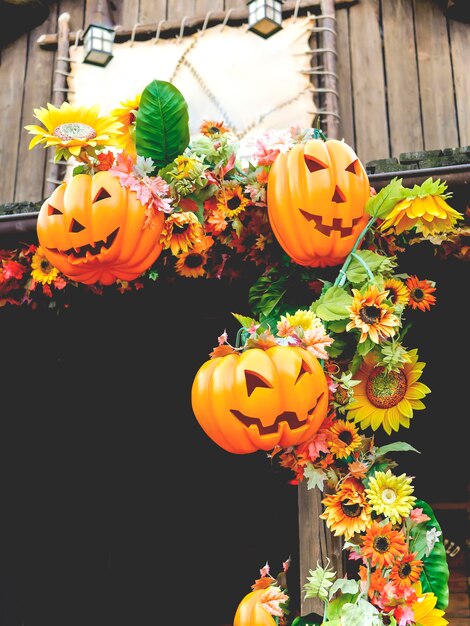 Halloween pumpkins with autumn flowers and decorations outside a house. Family fun activity, carved pumpkins into jack-o-lanterns for halloween