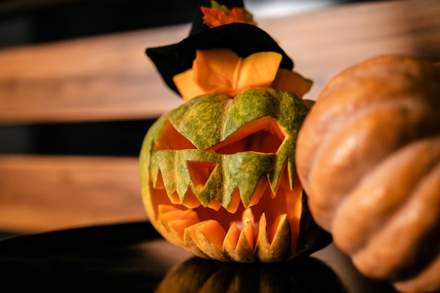 Foto zucche di halloween con cappello da strega nero sul suo, in legno