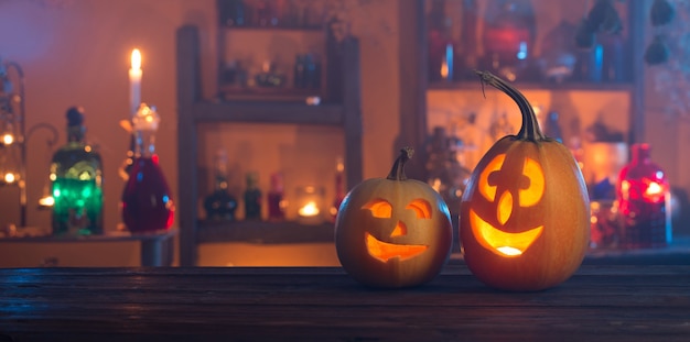 Halloween pumpkins with candles and magic potions at night indoor