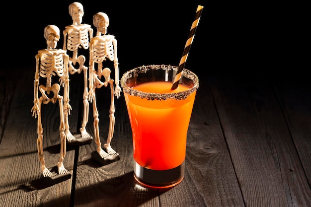 Halloween red cocktail Bloody Mary surrounded by skeletons