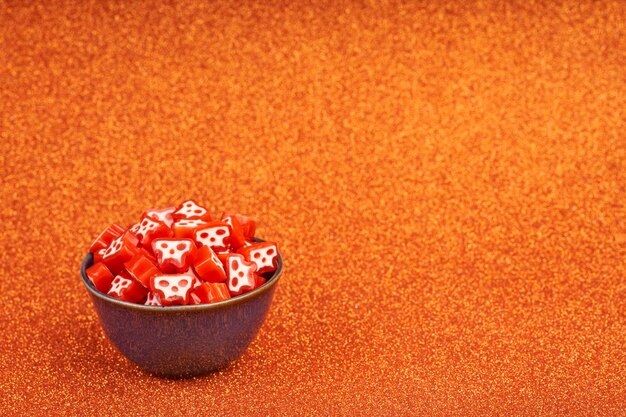 halloween red skull candy in bowl with orange bright background with horizontal copy space