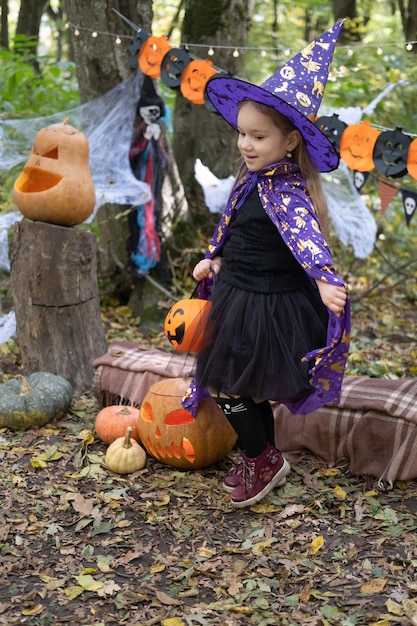 Halloween. schattig klein meisje in heksenkostuum met jack o lantern plezier buiten