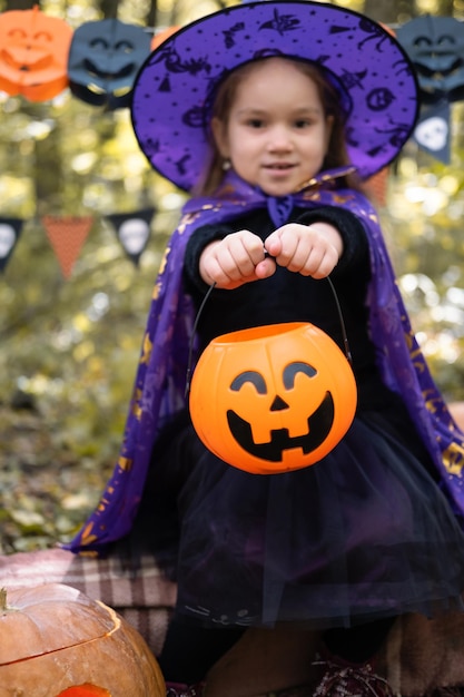 Halloween. schattig klein meisje in heksenkostuum met jack o lantern plezier buiten