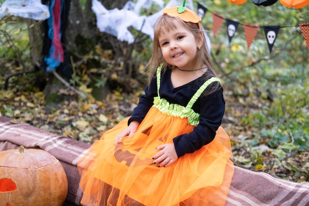 Halloween. schattig meisje in pompoenkostuum met pompoen buiten, plezier maken, halloween vieren