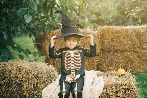 Halloween skeleton child Cheerful child and pumpkin on sunshine background Funny kids in carnival co