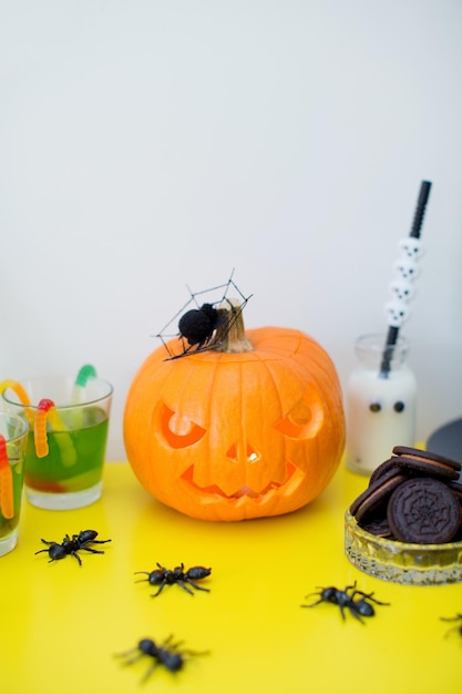 Halloween-snoepreep met snoep en gesneden pompoen op een gele tafel Halloween-feest met decoraties en eten thuis