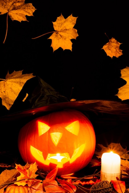 Хэллоуинские натюрморты красочная тема страшная украшенная темно-желтые кленовые листья комната с горящей тыквой подсвечник шляпа ведьмы на заднем плане желтые листья