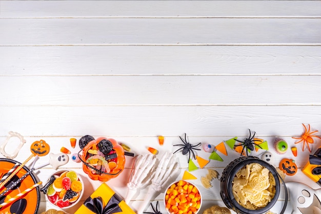 Halloween sweets and snacks table Set of Halloween dinner party foods candy snacks with holiday costume decorations pumpkin buckets wooden background top view copy space