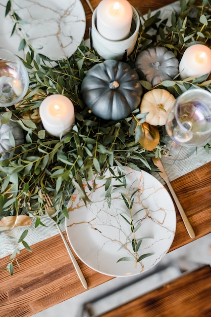 Halloween Table setting on dark background. Dish with sweets s on a dark table with black and gold pumpkin. Flat lay, top view trendy holiday concept.