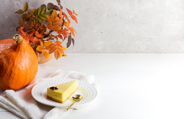 Halloween thanksgiving concept with pumpkin pie piece orange pumpkin fall leaves on white table