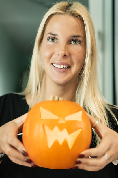 Halloween theme a girl at home with a carved pumpkin for the holiday in her hands