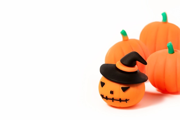 Halloween toy pumpkins on. Jack-o'-lantern in black hat with pumpkins around on white background with copy space.