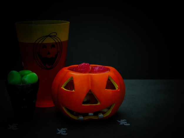 Halloween-traktatie in een keramische pompoen en in glazen op een zwarte achtergrond
