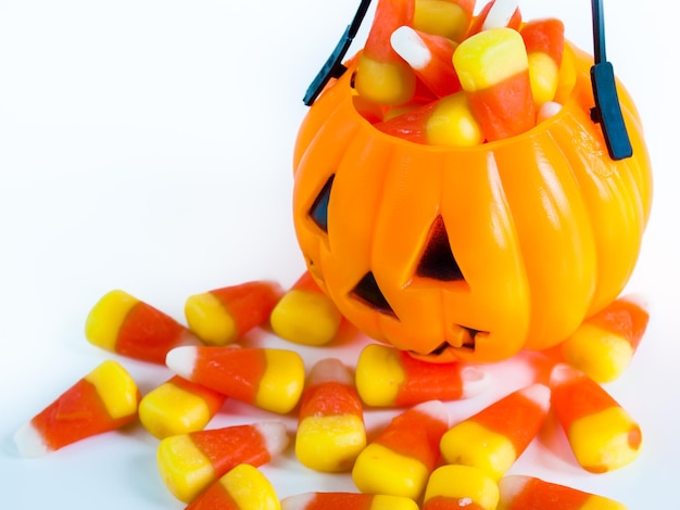 Halloween treat bag filled with candy corn candies on white background.