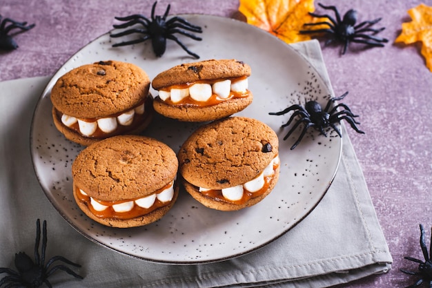 Foto halloween tratta i biscotti con denti di marshmallow su un piatto e ragni