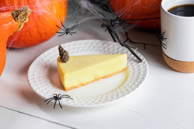 Halloween treats pumpkin pie piece cup of tea or coffee with pumpkins and black spiders on white