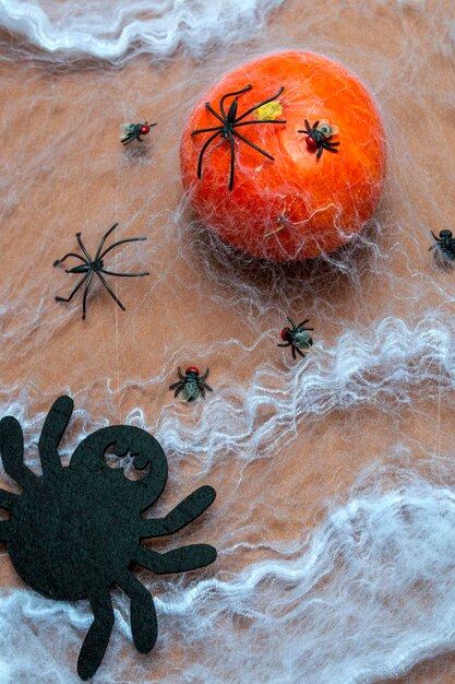 Halloween uitnodigingskaart concept. Pompoen in een spinnenweb met spinnen en vliegen close-up. Verticale foto.