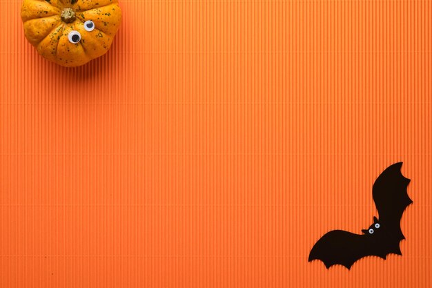 Halloween vakantie achtergrond oranje pompoen vleermuis met grappige ogen spin spinnenweb oude bladeren en takken van eng bos op oranje achtergrond Happy halloween kaart herfst decoratie bovenaanzicht