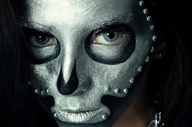 Halloween, vakantie, levensstijl, mensen, schoonheid, creatief concept-Halloween en creatieve make-up thema: mooi meisje model met zwart lichaam met zilveren masker schedel verf op donkere achtergrond in studio