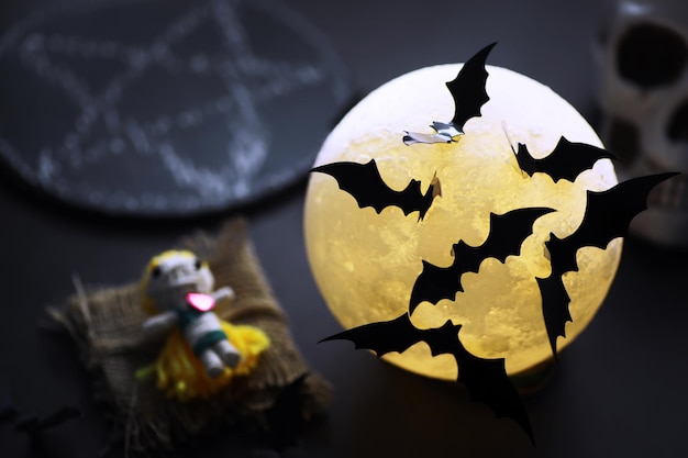 Halloween-vakantieconcept. Oude stenen tafel in de vorm van vleermuizen. Halloween papier decoraties op donkere achtergrond. Maan speelgoed.