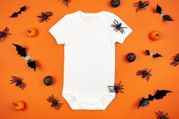 Halloween white baby girl or boy bodysuit mockup flat lay with pumpkins spiders and bats on orange background Design onesie template print presentation mock up Top view