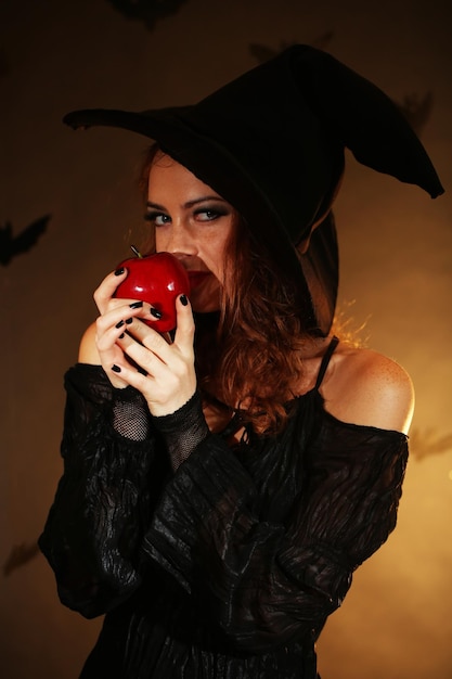 Foto strega di halloween con la mela su sfondo scuro