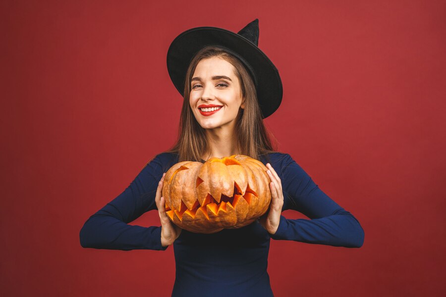 Premium Photo | Halloween witch with a carved pumpkin - isolated on red ...