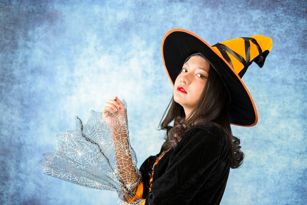 Halloween Witch with in dark blue background.Portrait young girl.