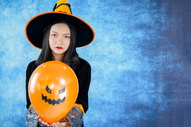 Halloween witch with evil balloon in dark blue background.