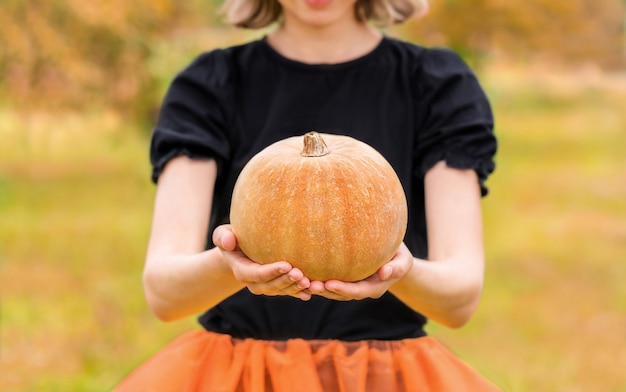 Halloween witch with pumpkin in her hands