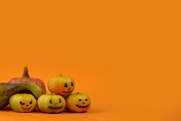 Halloween with pumpkins and funny faces on an orange background
