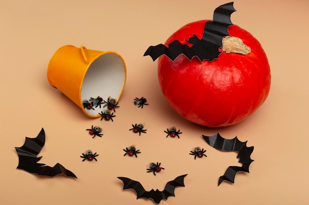 Halloween with pumpkins, spiders, yellow bucket, flies and a bat on a beige background. Halloween party concept