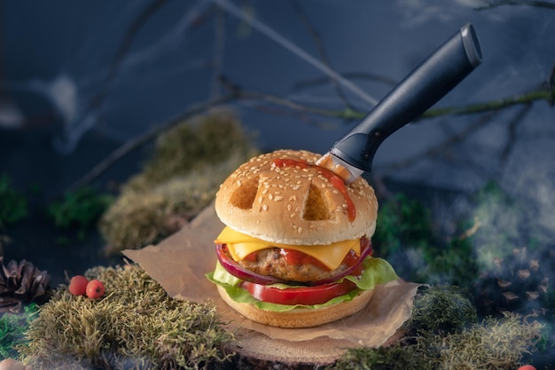 Halloweenburger in de vorm van een pompoenkoplantaarn in een mysterieus bos. Enge cheeseburger
