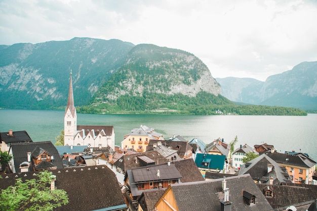 Photo hallstatt church with bell tower lake with alpine mountains on background